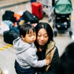 From Toddlers to Teens: Family Travel Tips by Age Group Personal chaotic airport/family moment with parent perspective, slightly off-center and candid, showing tired smiles amid mess.